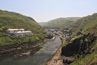 Boscastle Harbour with houses nestled in a green valley beside a narrow river and footpath.
